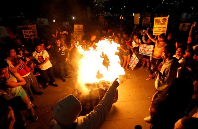 A Donald Trump pinata is burned by people protesting the election of Republican Donald Trump as the president of the United States in downtown Los Angeles, California U.S., November 9, 2016. (photo credit: REUTERS)