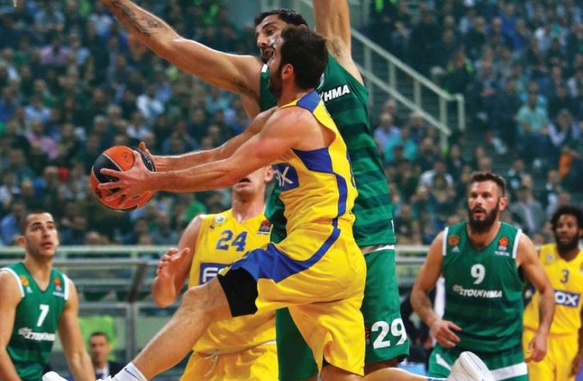 Maccabi Tel Aviv guard Yogev Ohayon drives to the basket against Ioannis Bourousis of Panathinaikos during last night’s 83-75 overtime loss for the yellow-and-blue in Greece. (photo credit: UDI ZITIAT)