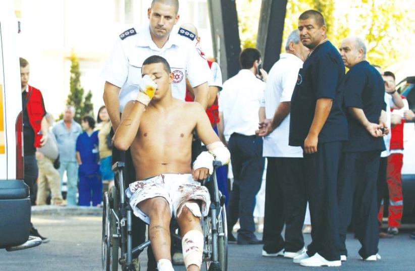 AN ISRAELI SURVIVOR of the Hezbollah bombing at Burgas, Bulgaria, on July 19, 2012, is wheeled to a waiting ambulance as he leaves the hospital. (photo credit: REUTERS)