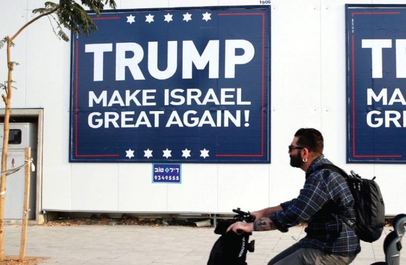 A man rides past a pro-Trump sign in Tel Aviv (photo credit: REUTERS)