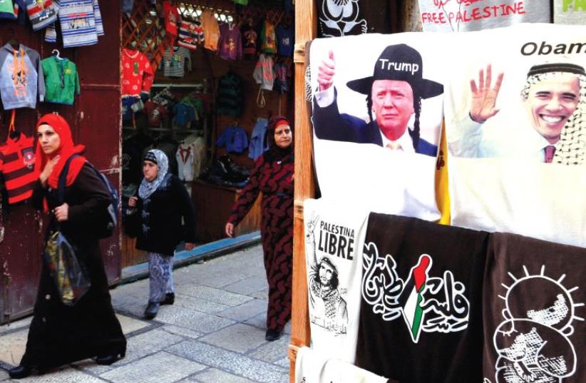Arab women walk past a shop in Jerusalem’s Old City displaying T-shirts with images of newly elected President Donald Trump (L) and outgoing President Barack Obama. (photo credit: REUTERS)