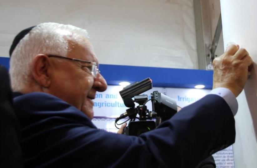 Israel President Reuven Rivlin places a Mezuzah at the Israeli exhibit booth at India premier agriculture fair.  (photo credit: TOVAH LAZAROFF)