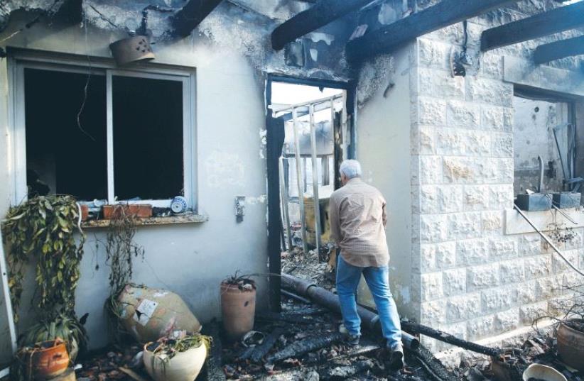 A MAN CHECKS damage to a house caused by the wildfire in Nataf, west of the capital, (photo credit: REUTERS)