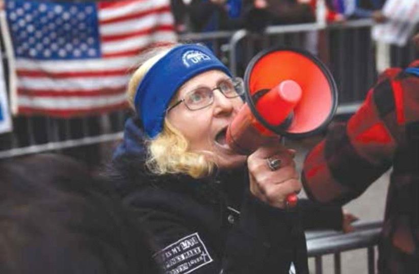 A woman protesting against US President-elect Donald Trump yells chants into a megaphone near Trump Tower in Manhattan on Sunday (photo credit: REUTERS)