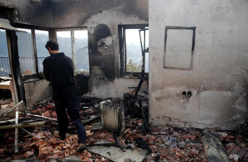 A man checks the damage to a house during a wildfire, in the communal settlement of Nataf, near Jerusalem November 23, 2016. (photo credit: REUTERS)