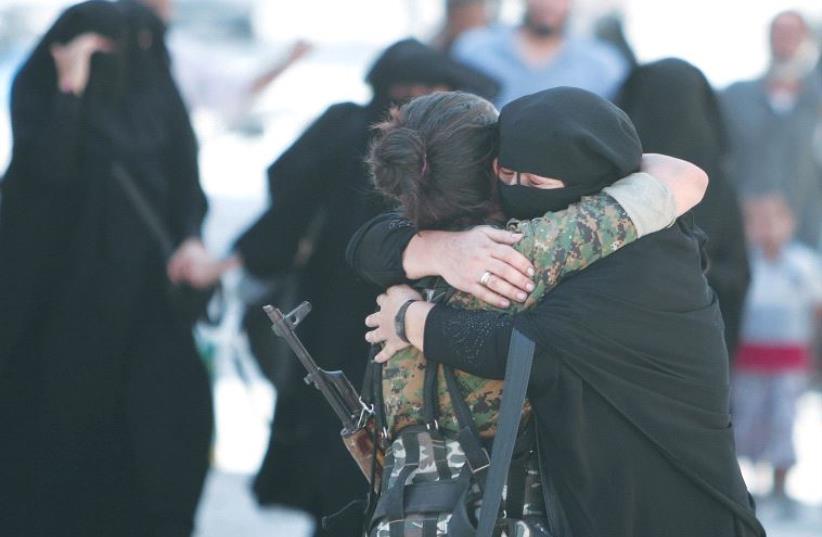 A WOMAN embraces a Syrian Democratic Forces fighter after being liberated from Islamic State control in the Syrian town of Manbij. (photo credit: REUTERS)