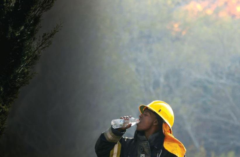 A firefighter drinks water as a wildfire burns in Haifa on Thursday last week (photo credit: REUTERS)