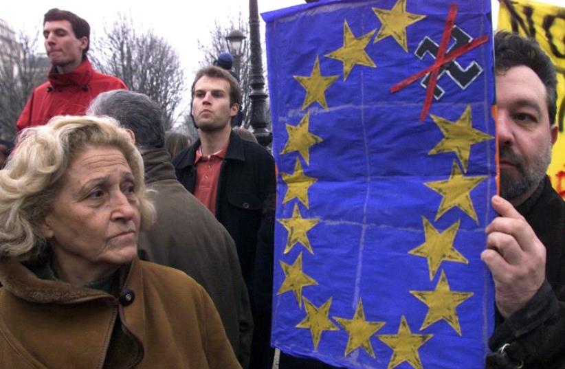 A protester with a mock European flag with a gold star representing Austria appearing as a swastika that has been crossed out [File] (photo credit: REUTERS)