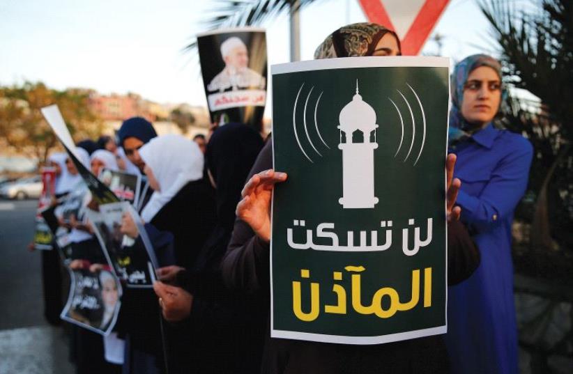 PROTESTERS AGAINST a law that would lower the volume of mosque loudspeakers hold a sign in Umm el-Fahm that reads, 'You will not silence the muezzin.' (photo credit: REUTERS)