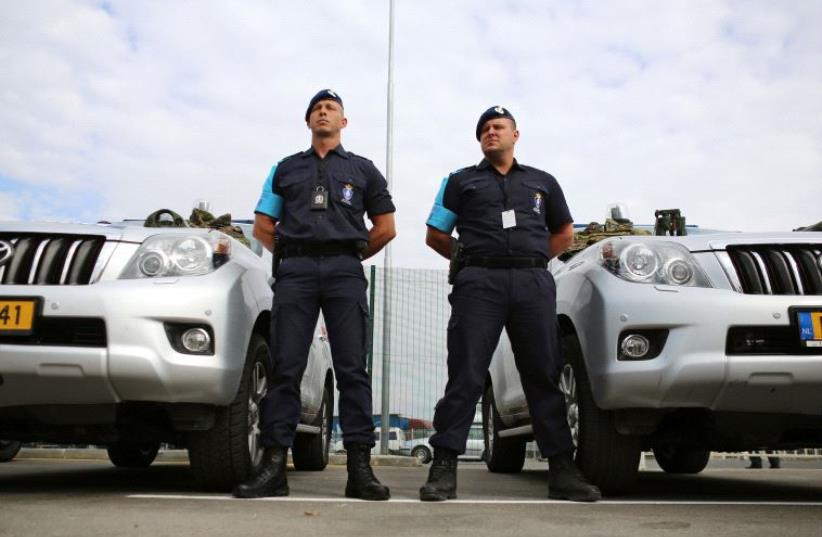 Border police from the Netherlands stand in front of their vehicles  (photo credit: REUTERS)