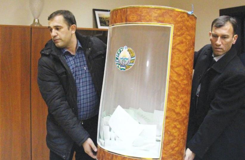MEMBERS OF a local electoral commission carry a ballot box after the presidential election in Tashkent, Uzbekistan, yesterday. (photo credit: REUTERS)