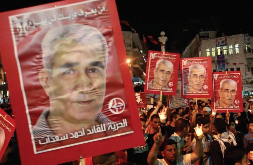 PALESTINIANS HOLD portraits of Ahmed Saadat, leader of the Popular Front for the Liberation of Palestine (PFLP), in Ramallah in 2012 (photo credit: REUTERS)