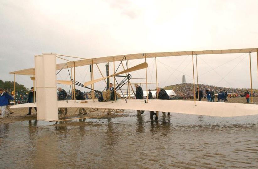 THE WRIGHT EXPERIENCE team rolls a Wright 1903 Flyer replica onto the field at the Wright Brothers National Memorial in Kill Devil Hills, North Carolina. (photo credit: REUTERS)