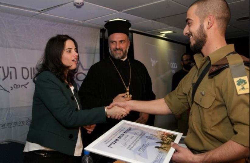 Caption: Justice Minister Ayelet Shaked and Father Gabriel Naddaf hand out an award to a Christian soldier (photo credit: CDC)