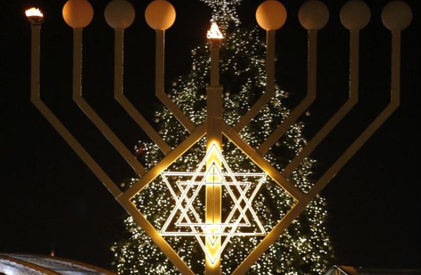 A giant menorah stands in front of a Christmas tree at the Brandenburg gate to celebrate Hanukkah in Berlin December 16, 2014 (photo credit: REUTERS)