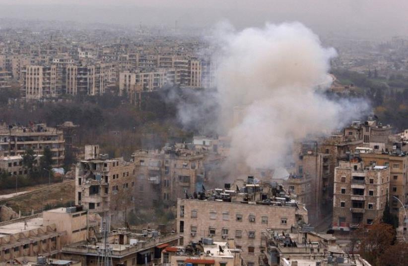 Smoke rises near Bustan al-Qasr crossing point in a government controlled area, during clashes with rebels in Aleppo, Syria December 5, 2016 (photo credit: REUTERS)
