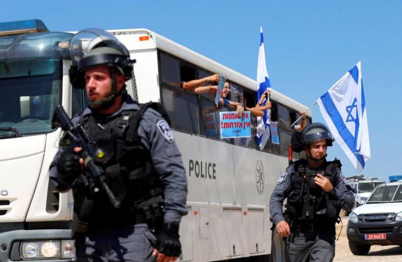 Israeli policemen walk near a police bus transporting right-wing Israeli protesters (photo credit: REUTERS)