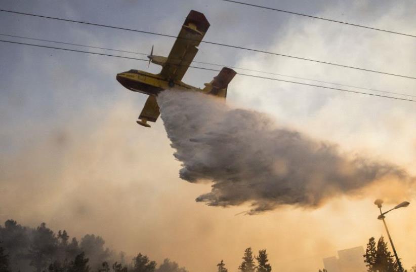 An Israeli firefighter plane helps extinguish a fire in the northern Israeli port city of Haifa on November 24, 2016 (photo credit: JACK GUEZ / AFP)