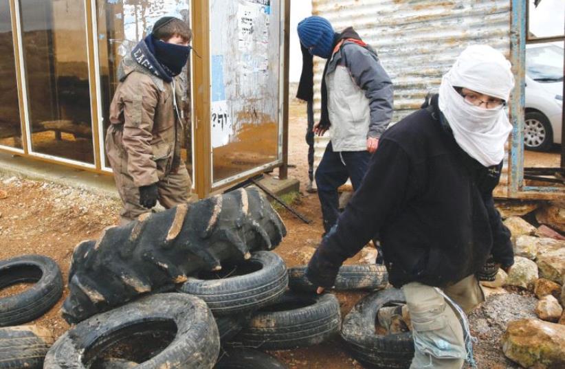 ISRAELI YOUTHS construct a barrier using tires in the settler outpost of Amona yesterday.  (photo credit: RONEN ZVULUN / REUTERS)