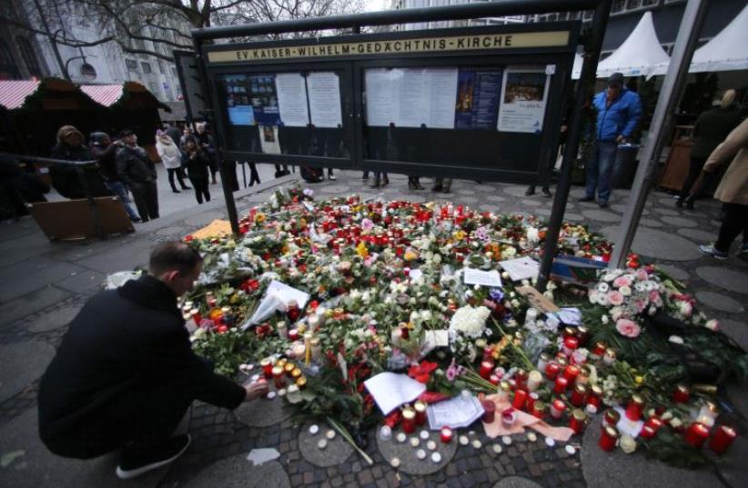 Flowers and candles are placed near the Christmas market in Berlin, Germany (photo credit: REUTERS)