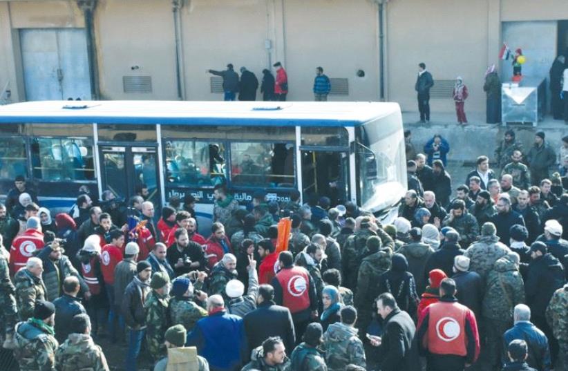 PEOPLE WAIT for buses after being displaced by fighting near Aleppo in Syria (photo credit: REUTERS)