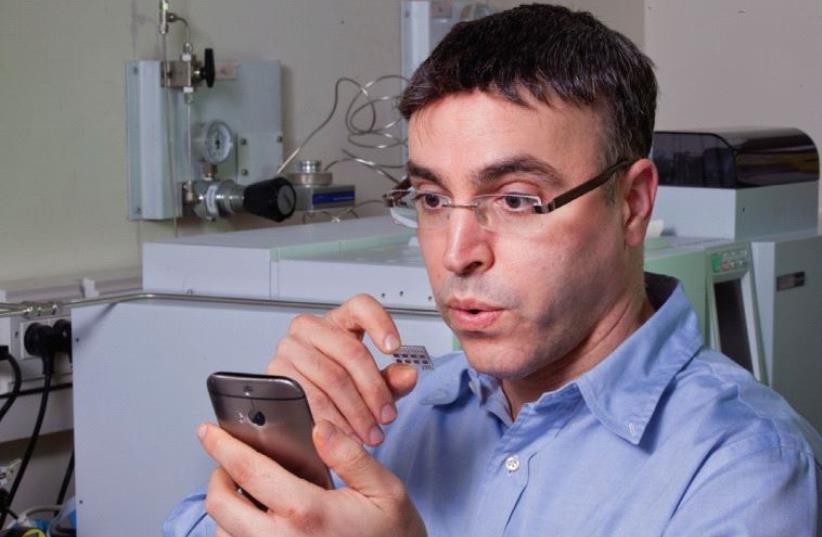 PROF. HOSSAM HAICK breathes on a sensor he developed that is capable of identifying various chronic diseases by analyzing components in a person’s breath. (photo credit: TECHNION)