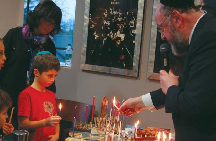PARTICIPANTS AT Limmud 2016 light Hanukka candles on Monday with British Chief Rabbi Ephraim Mirvis in Birmingham, England (photo credit: RANANA DINE)