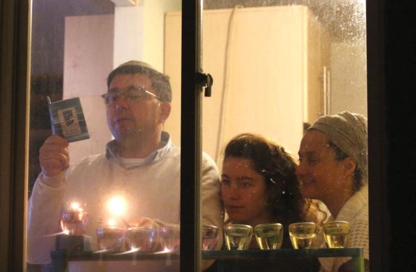 A family lighting a hanukkia (photo credit: MARC ISRAEL SELLEM)