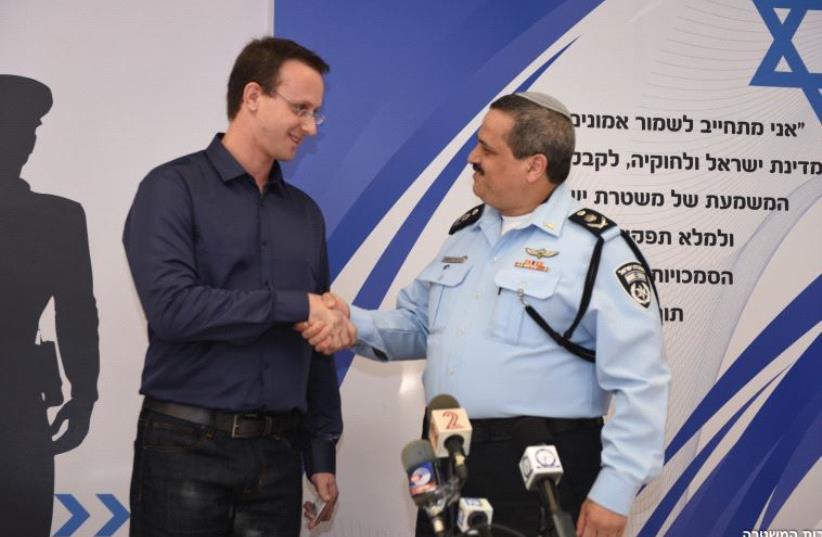 Police Insp.-Gen. Roni Alsheikh shakes hands with the 2,000th police recruit Dr. Ido Krone at the Bat Yam recruitment center on Thursday (photo credit: ISRAEL POLICE)