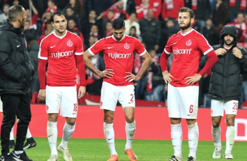 Hapoel Tel Aviv players Samuel Scheimann (left), Ofer Verta (center) and Adi Gotlieb (right) and the rest of their teammates were dejected following last night’s 1-0 loss at Maccabi Petah Tikva, which left the team three points ahead of the relegation zone ahead of a crucial week to its future. (photo credit: ADI AVISHAI)