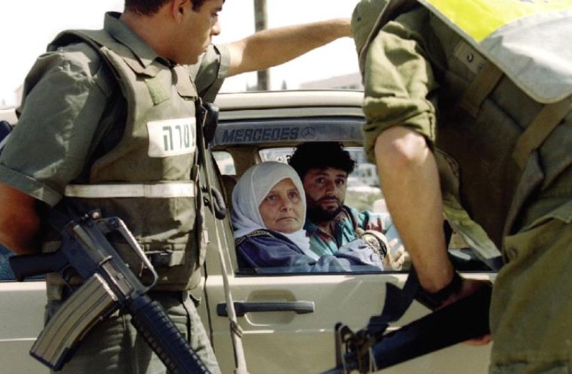 SOLDIERS AND Border Police question a Palestinian couple at a roadblock leading from the West Bank in 1995. (photo credit: REUTERS)