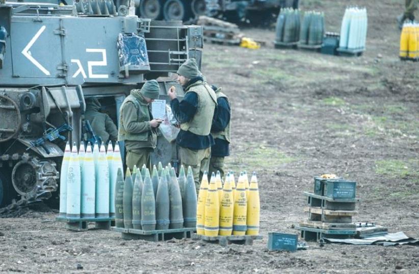 IDF SOLDIERS stand next to ammunition and a mobile artillery unit near the border with Syria last year. (photo credit: REUTERS)