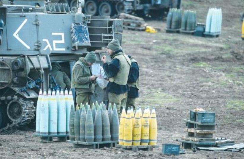 IDF SOLDIERS stand next to ammunition and a mobile artillery unit near the border with Syria last year. (photo credit: REUTERS)