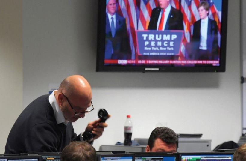 TRADERS AT BGC Partners in London look at their computer monitors as President-elect Donald Trump is seen speaking on a television screen after winning the US presidential election. (photo credit: REUTERS)
