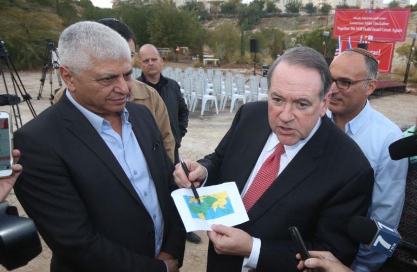 Mike Huckabee with Ma'ale Adumim mayor Beni Kashriel, pointing to Israel on a map of the world for journalists (photo credit: MARC ISRAEL SELLEM/THE JERUSALEM POST)
