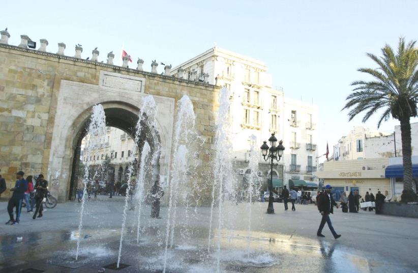People walk past the arch of Bab el-Bhar, also known as the French gate, at the entrance of the medina district in Tunis, last year (photo credit: REUTERS)