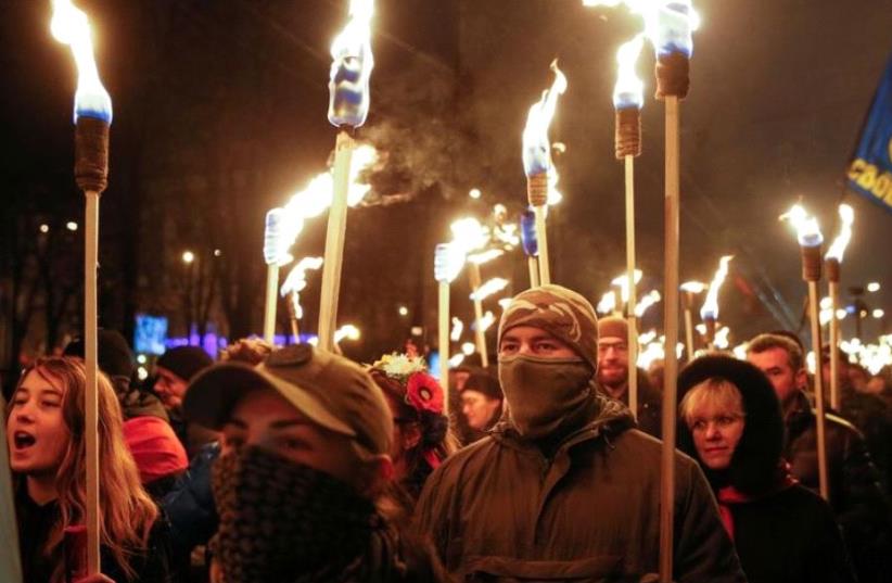 Activists of the Svoboda (Freedom) Ukrainian nationalist party hold torches as they take part in a rally to mark the 108th birth anniversary of Stepan Bandera (photo credit: REUTERS)