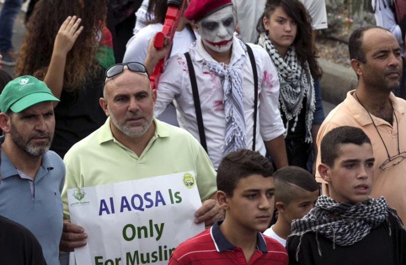 Israeli Arabs take part in a pro-Palestinian rally. One protester holds a sign stating "Al-aqsa [Temple Mount] is Only for Muslims" (photo credit: REUTERS)
