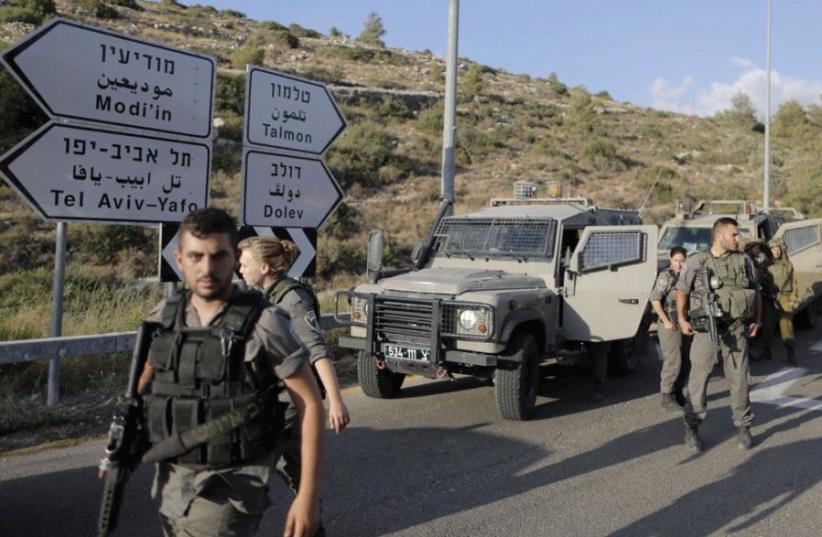 BORDER POLICE officers search the area around the settlement of Dolev after the shooting attack of Danny Gonen in June 2015. (photo credit: REUTERS)