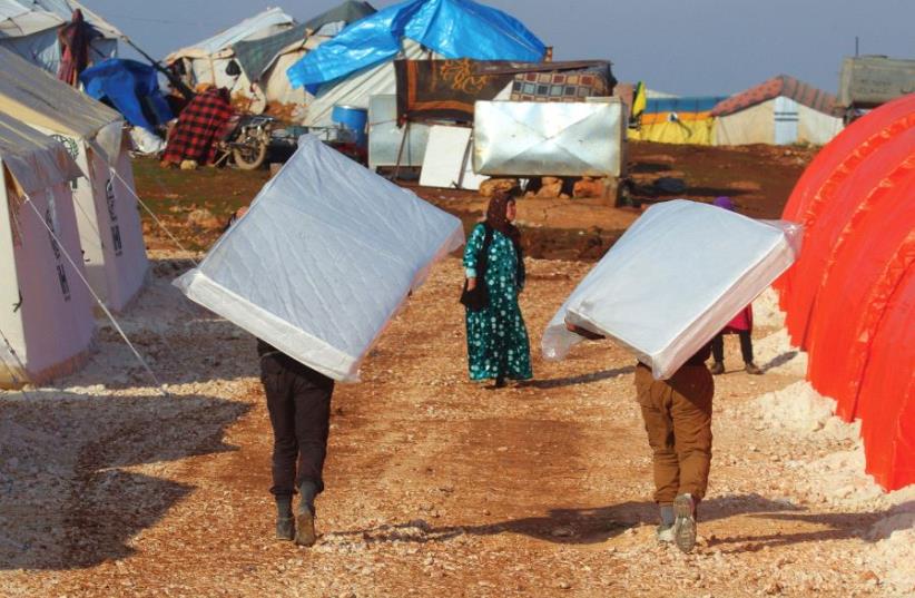 EVACUEES from a rebel-held area of Aleppo carry mattresses they received in the Kamouneh camp in Syria last month (photo credit: REUTERS)