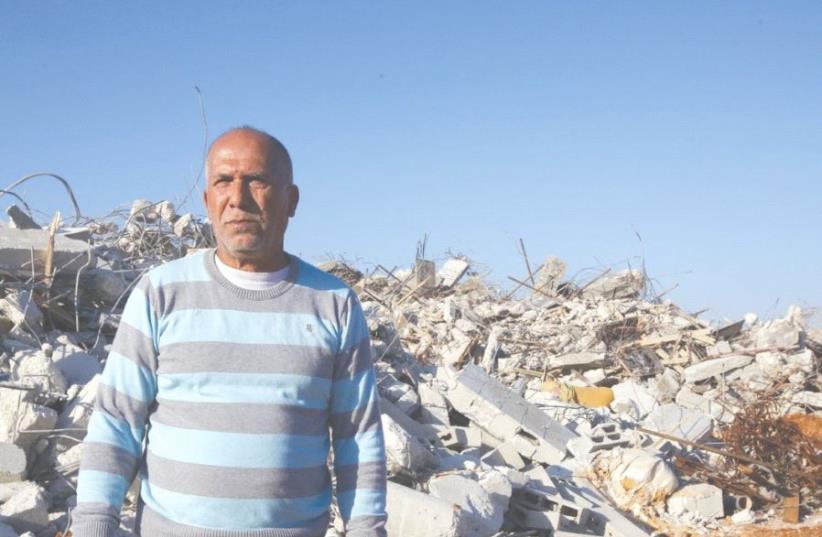 KALANSUWA RESIDENT Yusuf Makhlouf poses yesterday before the rubble of one of the 11 illegally built homes demolished by the government. (photo credit: MARC ISRAEL SELLEM/THE JERUSALEM POST)