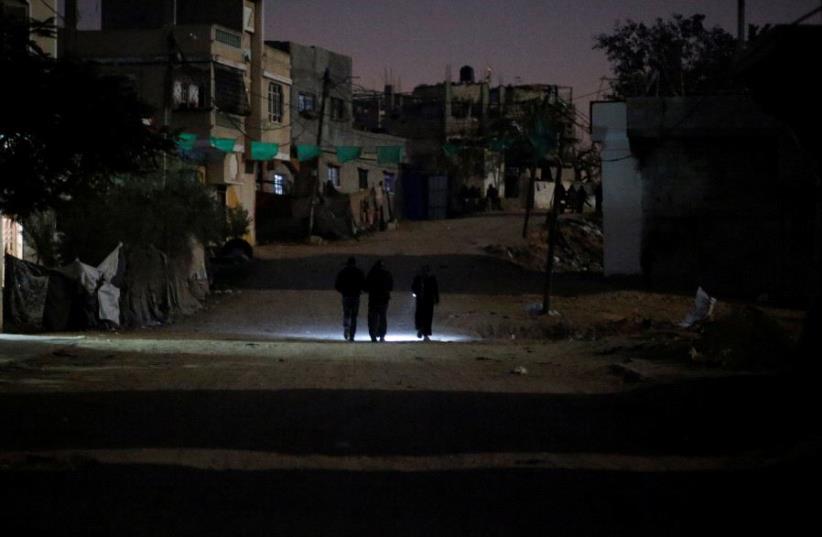 Palestinians walk on a road during a power cut in Beit Lahiya in the northern Gaza Strip. (photo credit: REUTERS)