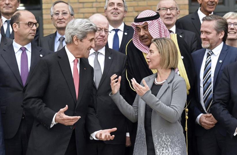 US Secretary of State John Kerry speaks with European Union Foreign Policy Chief Federica Mogherini as they take part with other foreign ministers and representatives in a family picture during the Mideast peace conference in Paris, France, January 15, 2017.  (photo credit: REUTERS)