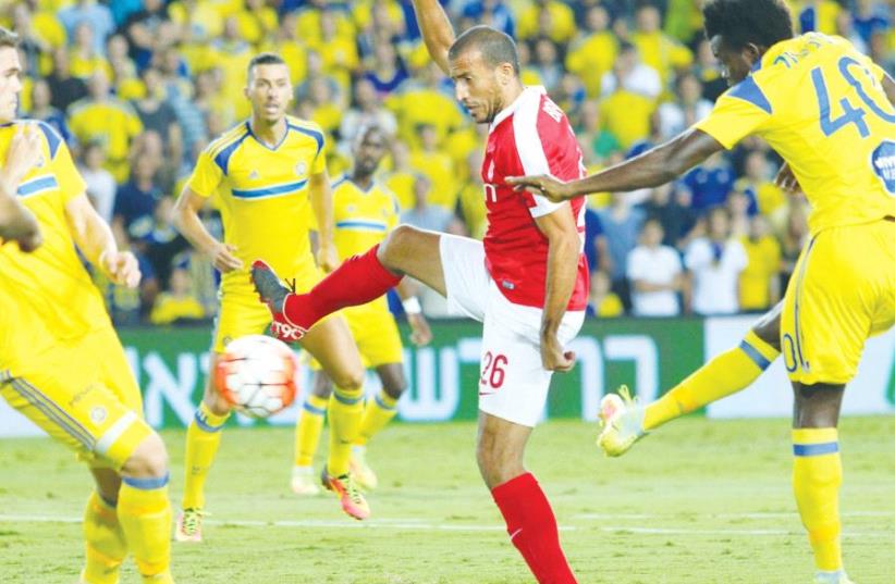 Hapoel Tel Aviv midfielder Avihai Yadin (center) is one of only five of his team’s players to survive from the side that lost 5-0 to Maccabi Tel Aviv in the last derby in September, with Maccabi’s Nosa Igiebor (right) scoring the opener in that match. (photo credit: ADI AVISHAI)