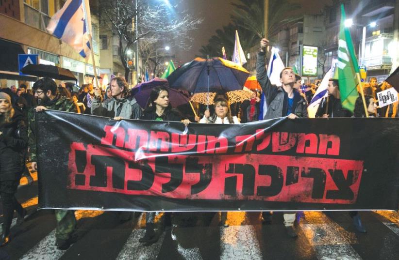 LEFT-WING PROTESTERS march during a demonstration calling for the resignation of Prime Minister Benjamin Netanyahu over police investigations for suspected corruption last week in Tel Aviv. The banner reads: ‘A corrupted government has to go.’ (photo credit: REUTERS)