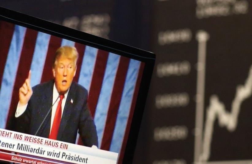A TV SCREEN showing President-elect Donald Trump is pictured in front of the German share price index, DAX board, at the stock exchange in Frankfurt, Germany, in November (photo credit: REUTERS)
