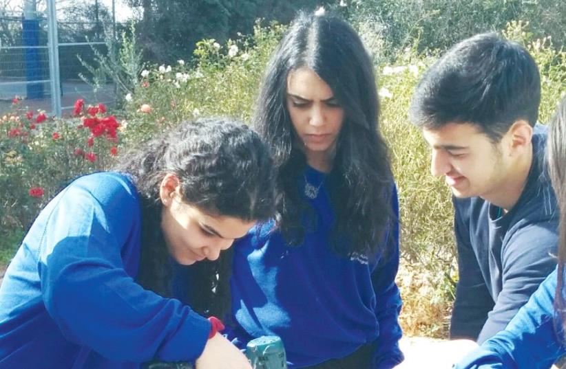 YESHIVA UNIVERSITY students Nora Shokrian, Shanee Carmel and Orley Bral build picnic tables in Halamish where the wooden tables and benches in the public parks were consumed by wildfires in November. (photo credit: YESHIVA UNIVERSITY)