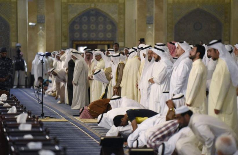 Sunni and Shi'ite worshippers, together with Emir Sheikh Sabah al Ahmed al Sabah, pray at the Grand Mosque of Kuwait, in Kuwait City [File] (photo credit: REUTERS)