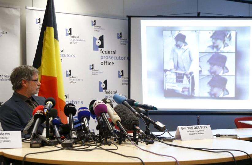 Belgian federal prosecutor Eric Van Der Sypt looks at CCTV images of a suspect in the attack which took place at the Brussels international airport of Zaventem, projected on a screen during a news conference in Brussels, Belgium April 7, 2016 (photo credit: REUTERS)
