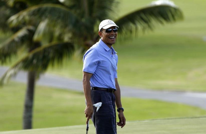 Barack Obama smiles as he plays golf in Hawaii (photo credit: REUTERS)